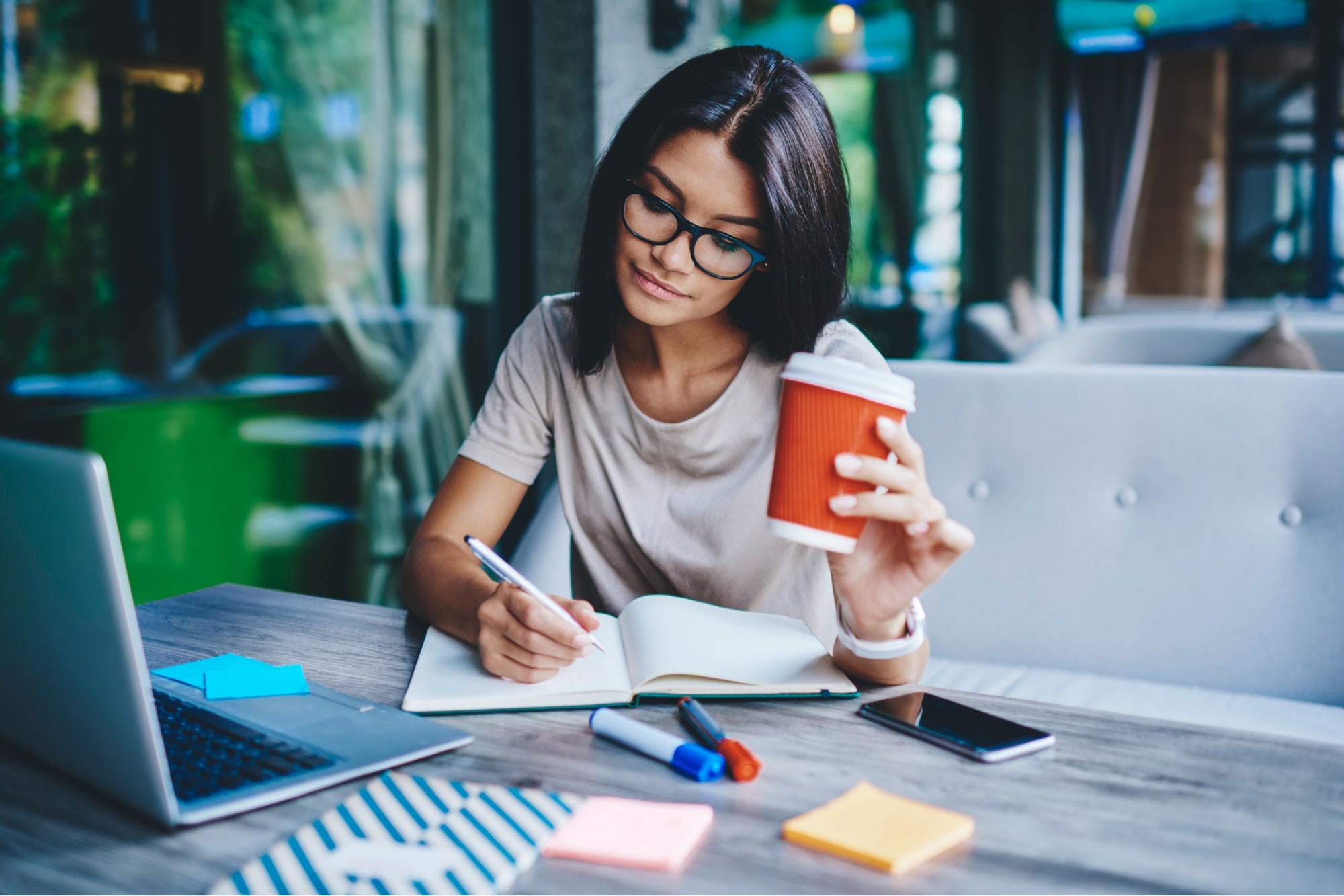 a woman writing on her desk, doing her freelance work