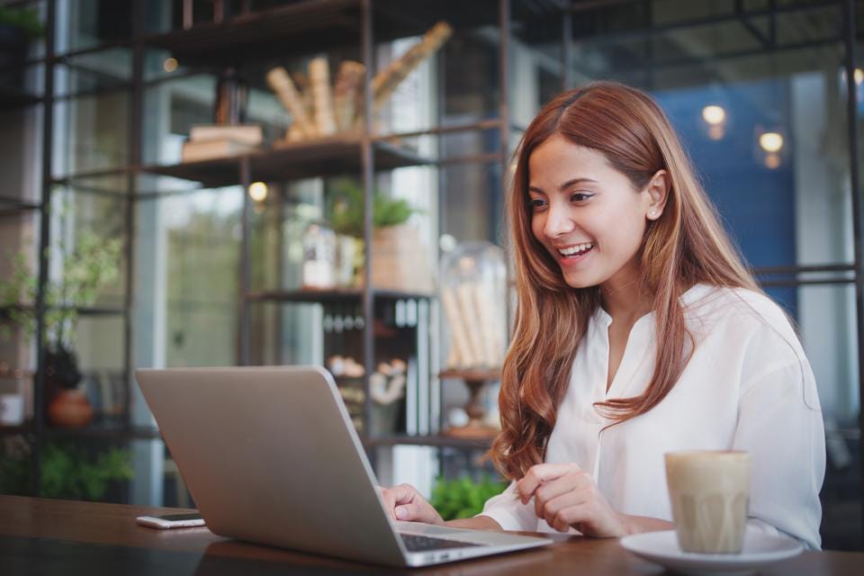 how to win your client as a freelancer, woman working on her laptop happily
